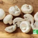 Champignons de Paris bio entiers et tranchés sur une planche en bois, avec logo AB