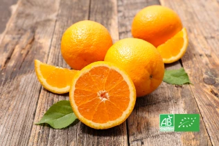 Oranges bio entières et coupées sur une planche en bois, avec logo AB