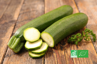 Courgettes bio entières et en rondelles sur une planche en bois, avec logo AB